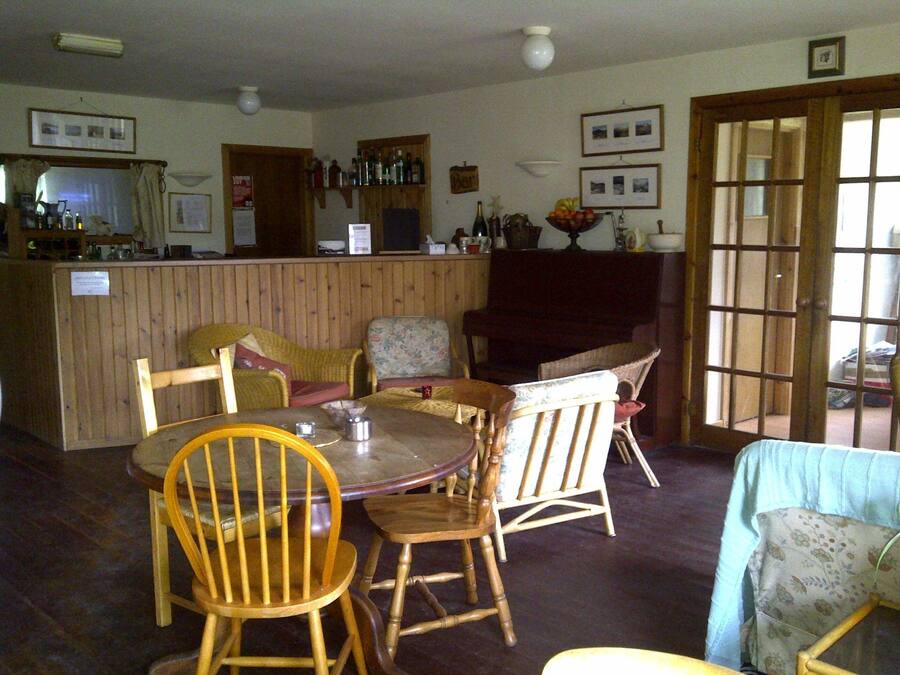A cozy room with a wooden bar, several chairs, a table, and a fireplace.