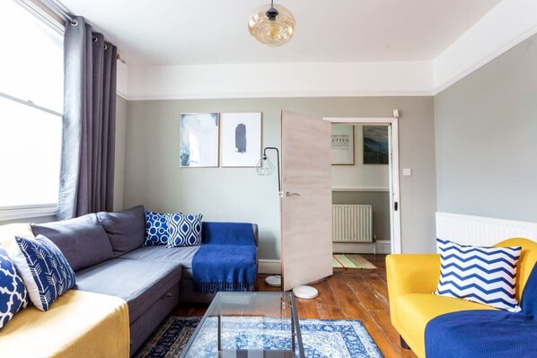 Una sala de estar moderna con un sofá, un sillón amarillo y una mesa de centro de vidrio.