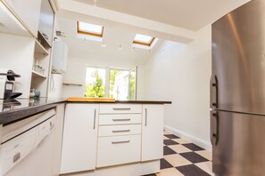 A modern kitchen with white cabinetry, a stainless steel refrigerator, and a black and white checkered floor.