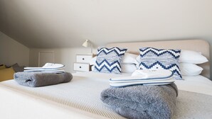 A neatly made bed with towels and pillows, a bedside table with a lamp, and a nightstand with a drawer. - The Jericho Escape - Comfortable & Modern 4BDR in Jericho (Oxford)