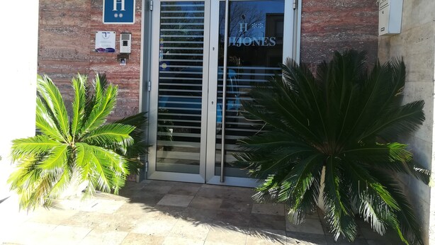 A hotel entrance with a sign reading "H. JONES" and a blue sign with a white 'H' and stars. - Hostal Jijones (Villarrubia de los Ojos)