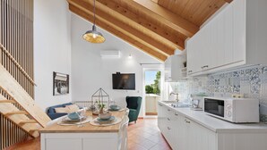 Una cocina moderna con armarios blancos, techo de madera y salpicadero de azulejos.