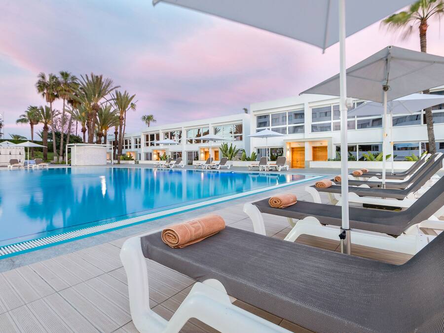 Una piscina al aire libre, sombrillas, sillones reclinables de piscina