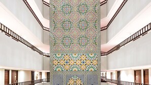 Un atrio de varios niveles con una columna decorativa central y un suelo con diseño.