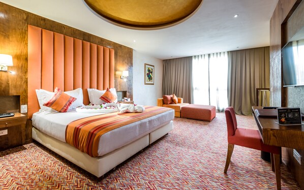 Habitación de hotel con una cama grande, un escritorio, una silla y un televisor.