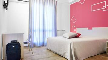 Una habitación de hotel con cama, escritorio, silla y maleta.