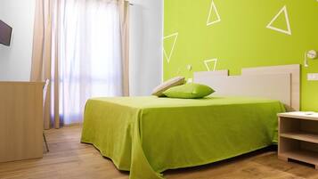 A room with a bed, a desk, and a window with curtains.