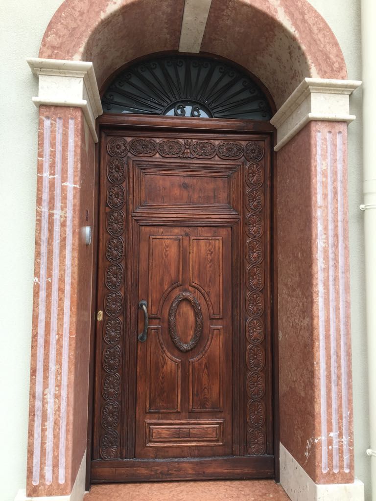A wooden door with intricate carvings and a circular medallion, set within an arched doorway.