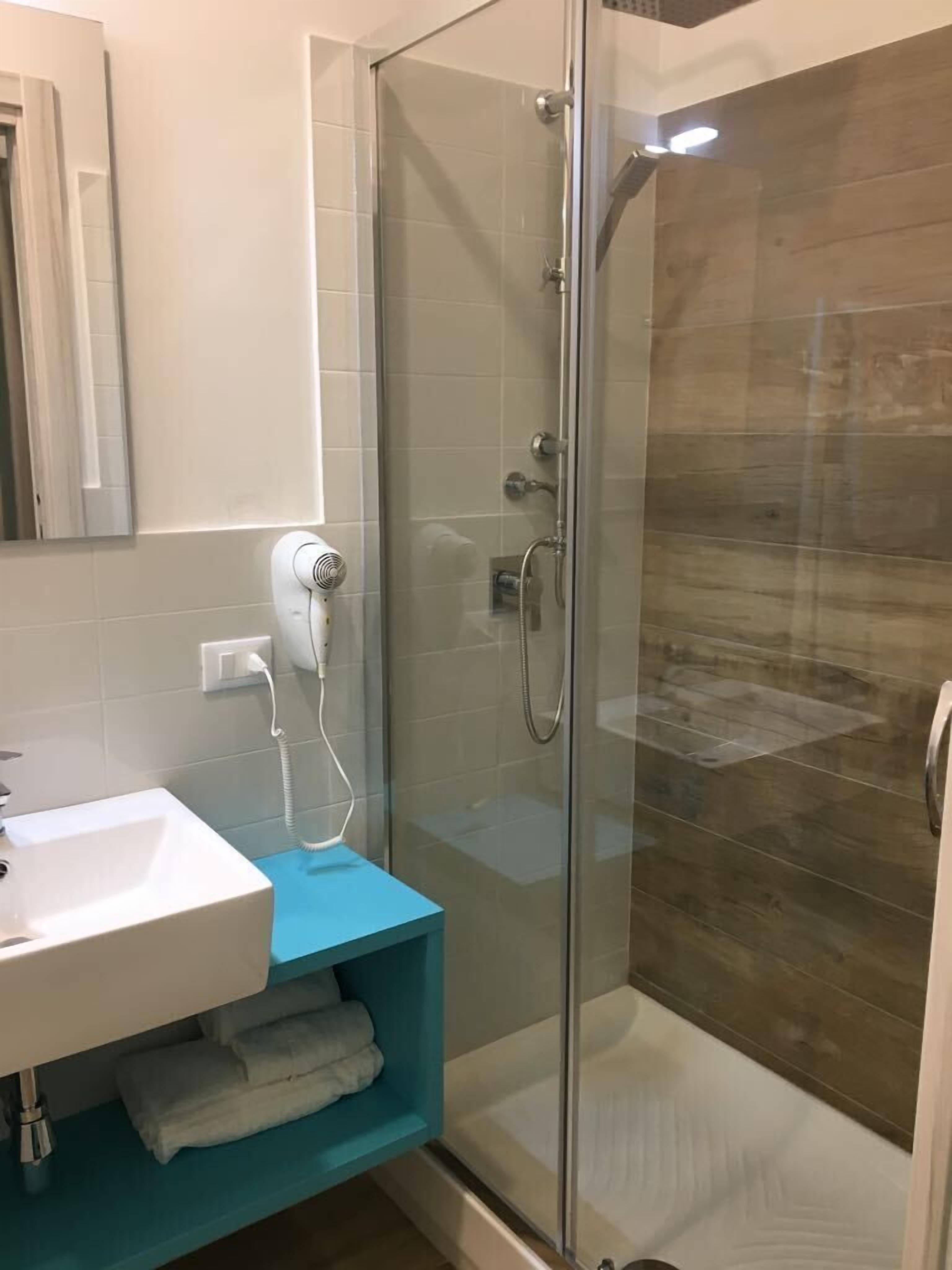A modern bathroom with a glass-enclosed shower, a white sink, and a blue vanity.