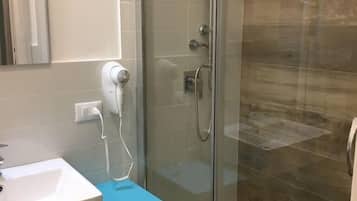 Ein Badezimmer mit einer Duschkabine, einem weißen Waschbecken und einem blauen Regal mit Handtüchern.