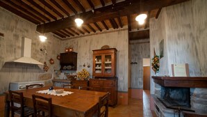 Una cucina rustica con un tavolo di legno, sedie, un fornello e un armadietto.