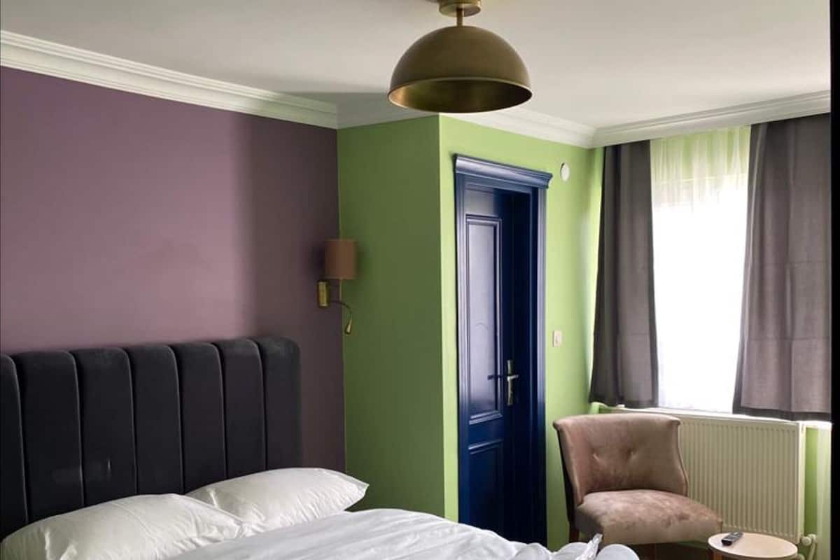 Una habitación de hotel con una cama, una silla, una puerta y una ventana con cortinas.