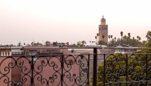 A view of a cityscape with a prominent tower and palm trees. - Amour d'auberge - Hostel (Marrakech)