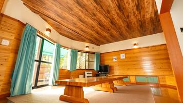 A wooden-paneled room with a large table, curtains, and a television.