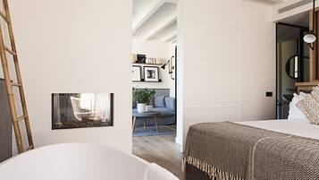 A modern bedroom with a large bed, a bedside table, and a mirror. There is a window with a view of a living room and a staircase.