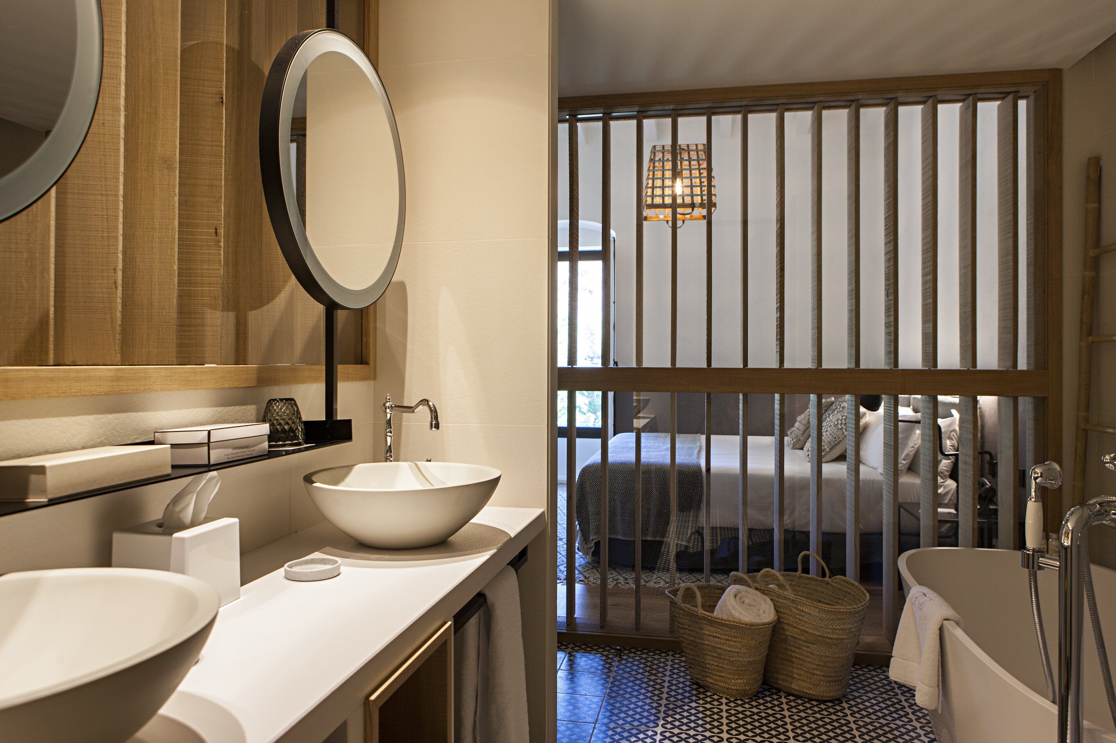 A modern bathroom with a large white sink, a round mirror, and a bathtub.