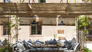 Ein Sitzbereich im Freien mit einer Couch, Kissen und hängenden Laternen.
