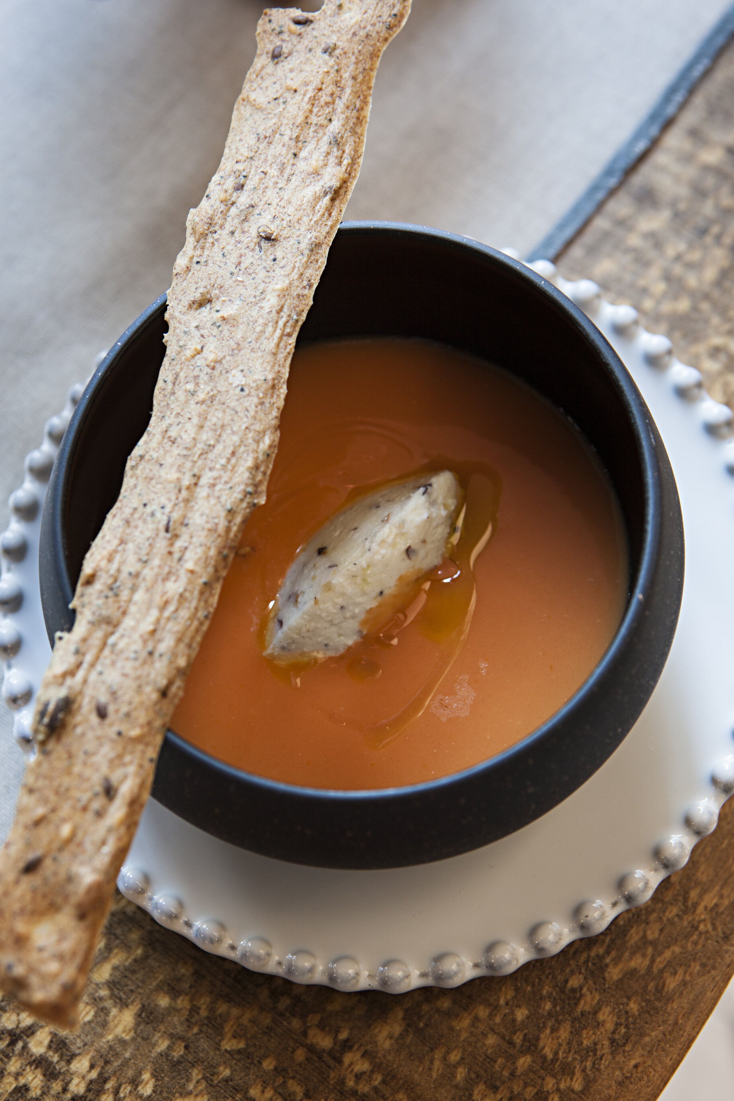 Un tazón de sopa con una rebanada de pan al lado.