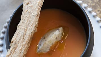 Un tazón de sopa con una rebanada de pan al lado.