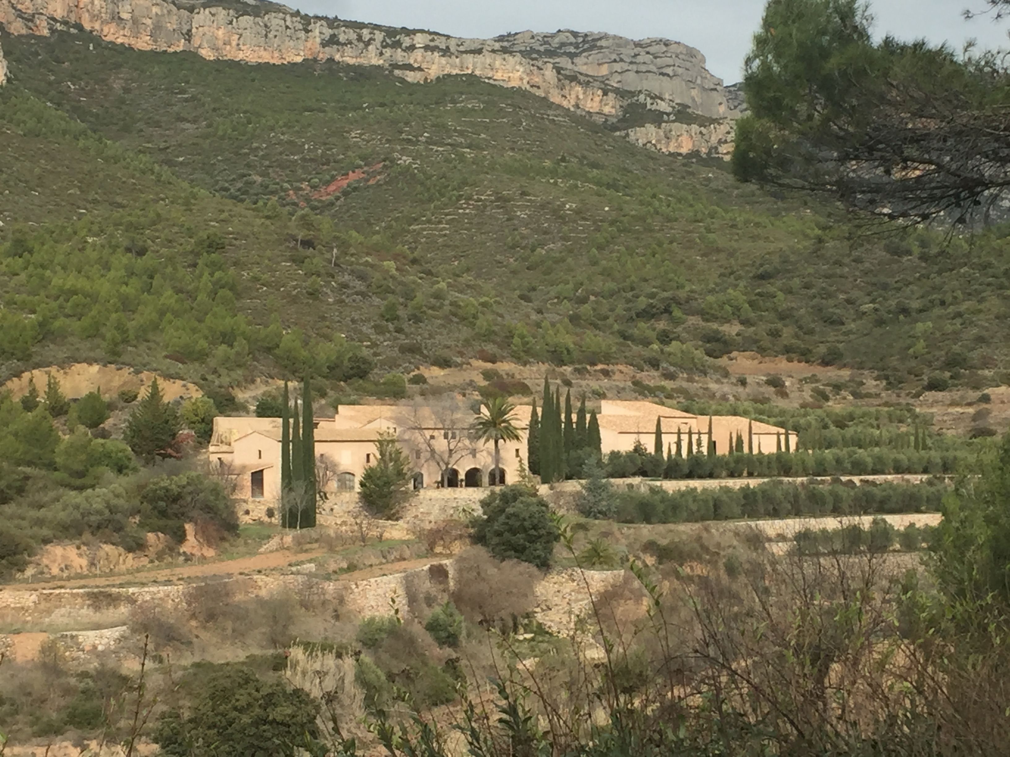 Un edificio tradicional con patio interior, rodeado de paisaje natural y acantilados rocosos.