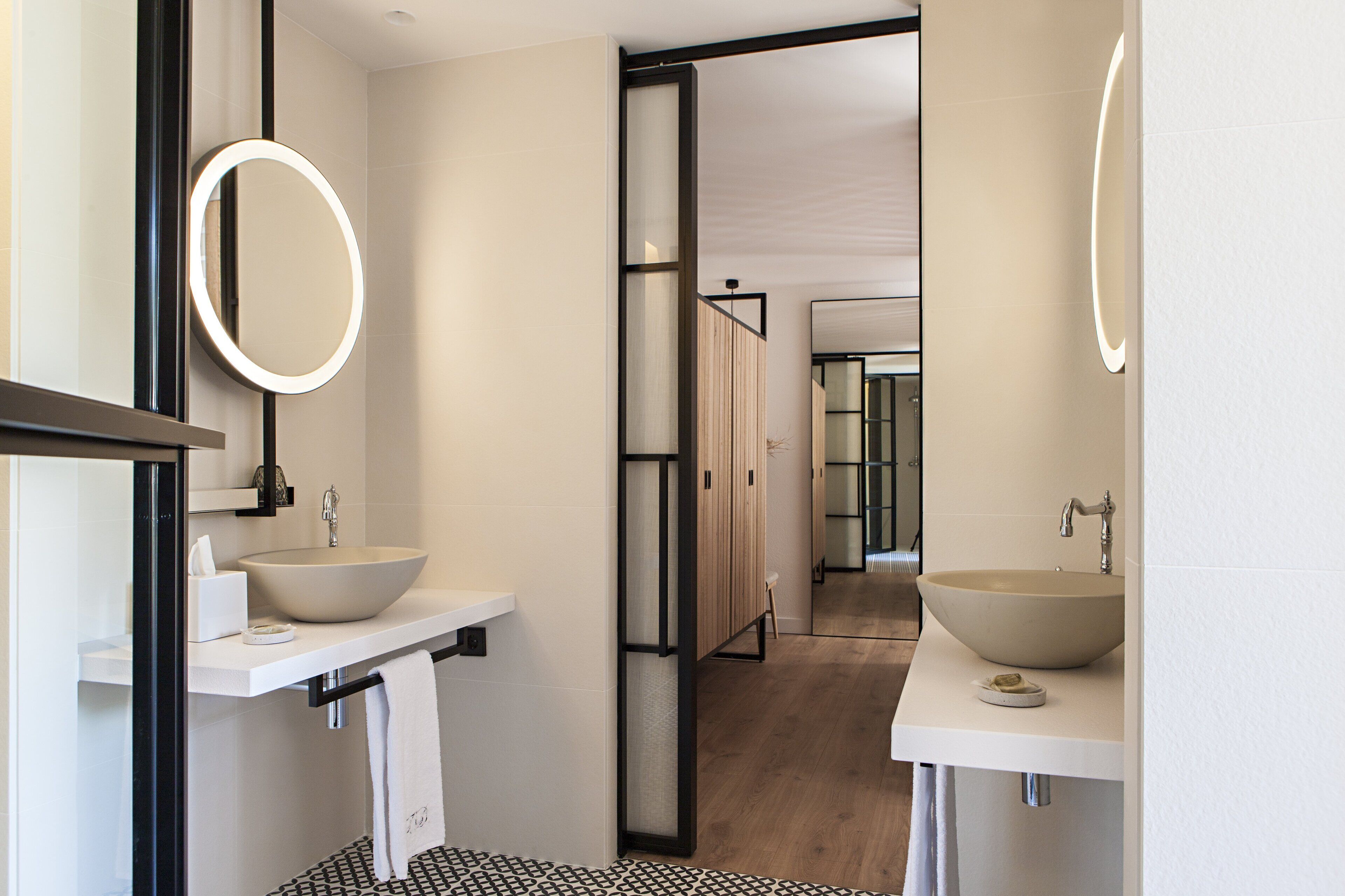 Un baño moderno con dos lavamanos grandes, un espejo y un suelo con diseño blanco y negro.