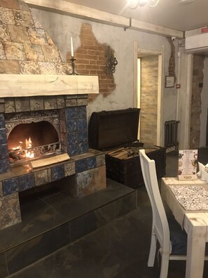A cozy room with a fireplace, a table with a coffee menu, and a rustic brick wall. - Hotel Centralnyi (Poltava)