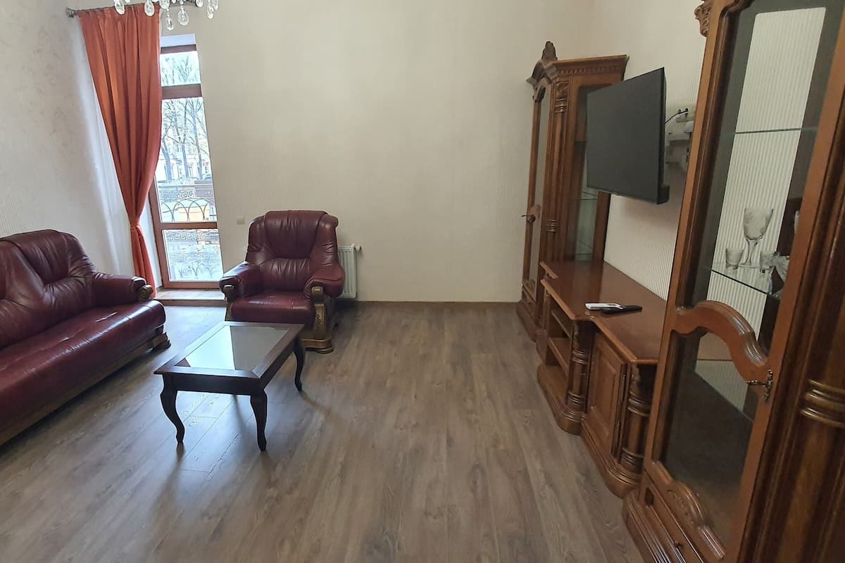 A living room with a leather sofa, a glass coffee table, and a wooden cabinet with a TV.