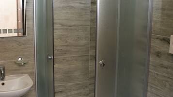 Une salle de bain moderne avec une douche à parois de verre, un lavabo blanc et des toilettes.