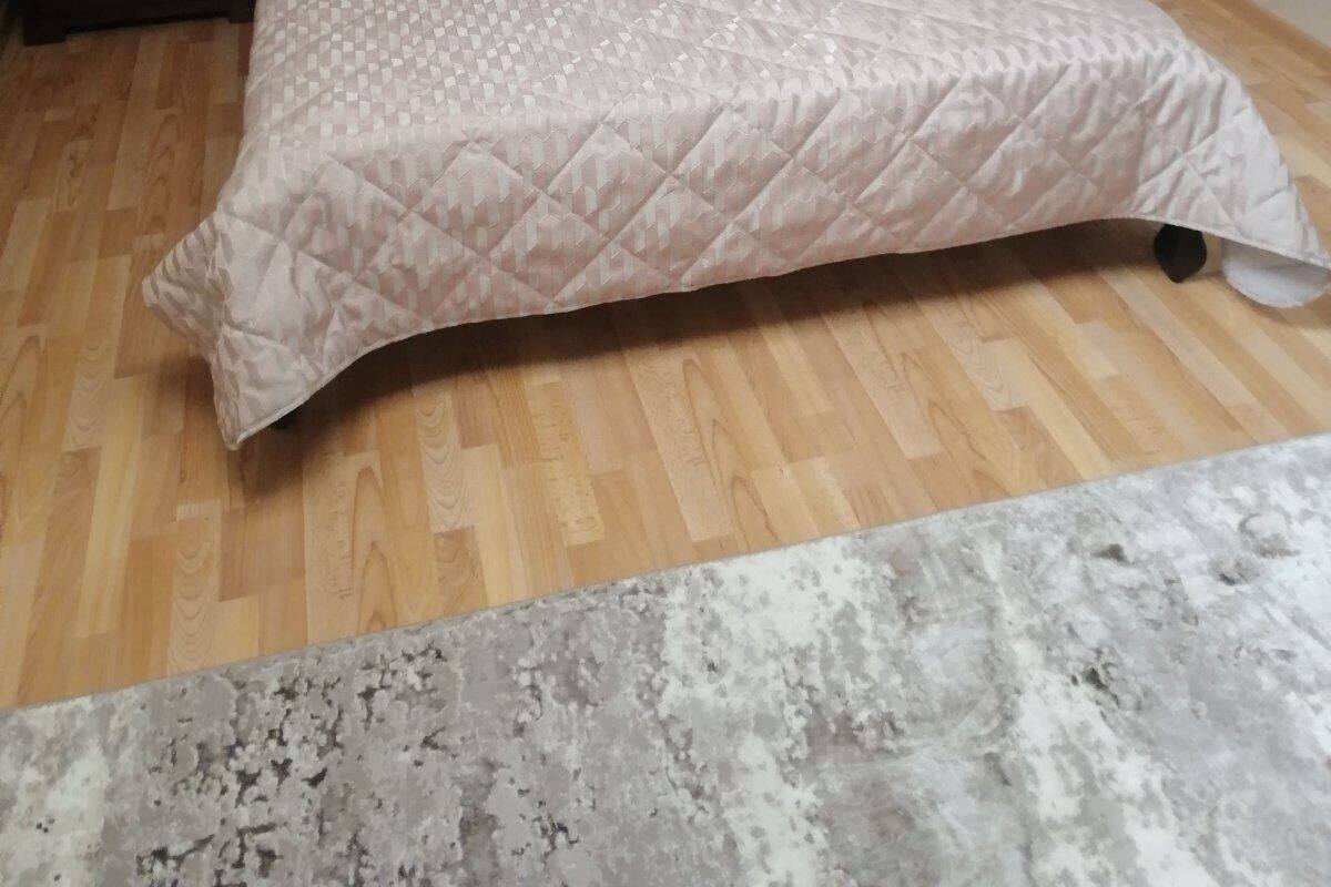 A bedroom with a bed, wooden floor, bedside tables, and a rug.