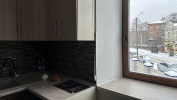 Eine Küche mit Holzschränken, einer gefliesten Spritzschutzwand und einem Fenster mit Blick auf eine verschneite Straße.