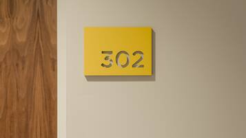 A yellow sign with the number 302 on a plain wall.