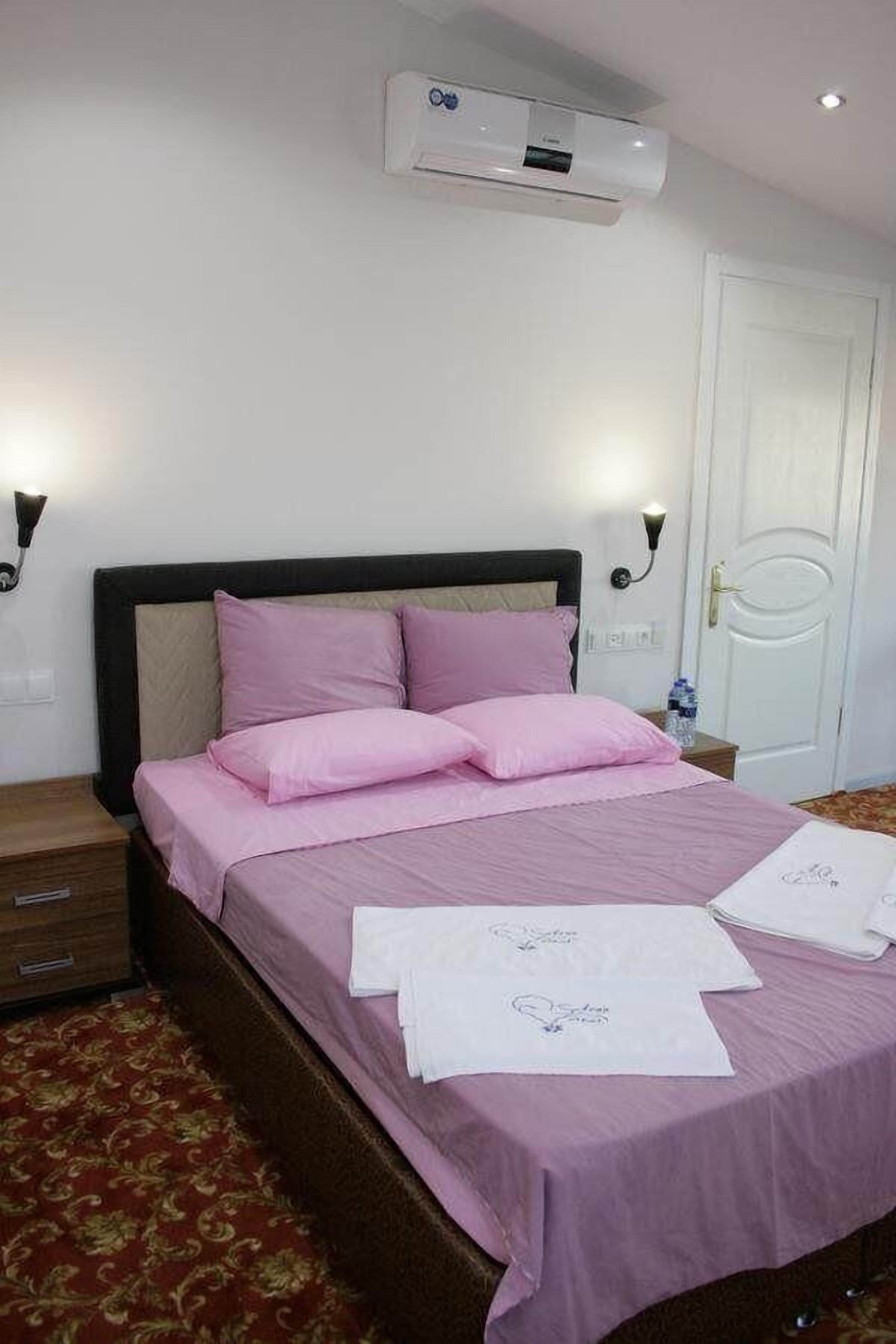 A bedroom with a bed, a nightstand, an air conditioning unit, and a door.