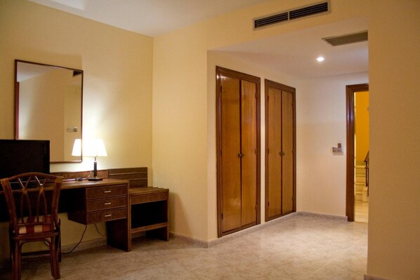 A room with a desk, chair, and a mirror. There are two wooden wardrobes and a door leading to another room. - Hotel Perales (Talavera de la Reina)