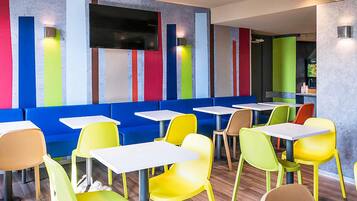 Un interior de restaurante moderno con asientos coloridos, una televisión de pantalla plana y una zona de bar.