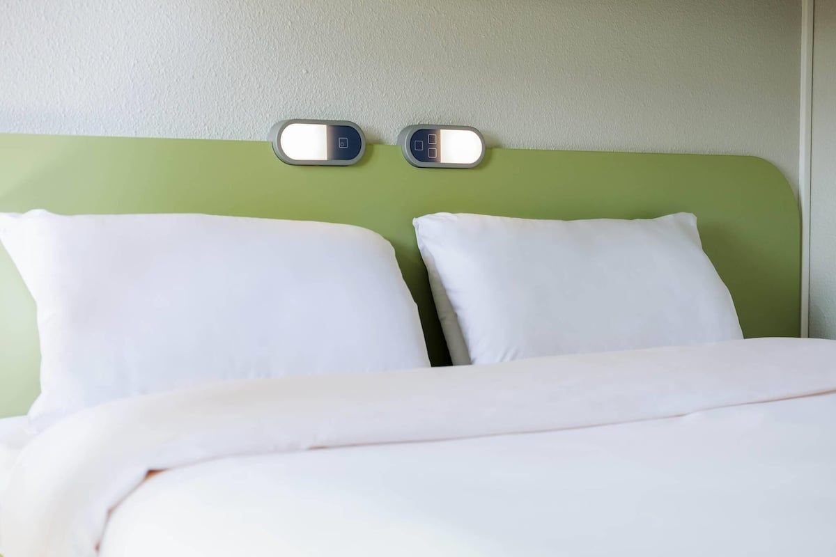 A bed with two white pillows and a green headboard.