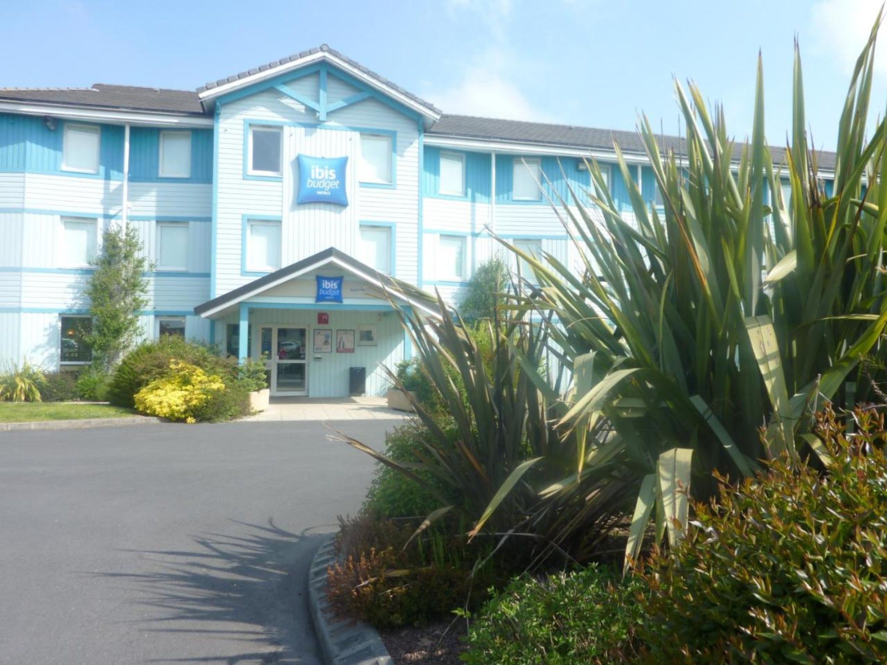 A two-story hotel with a blue exterior and a sign reading "ibis budget."