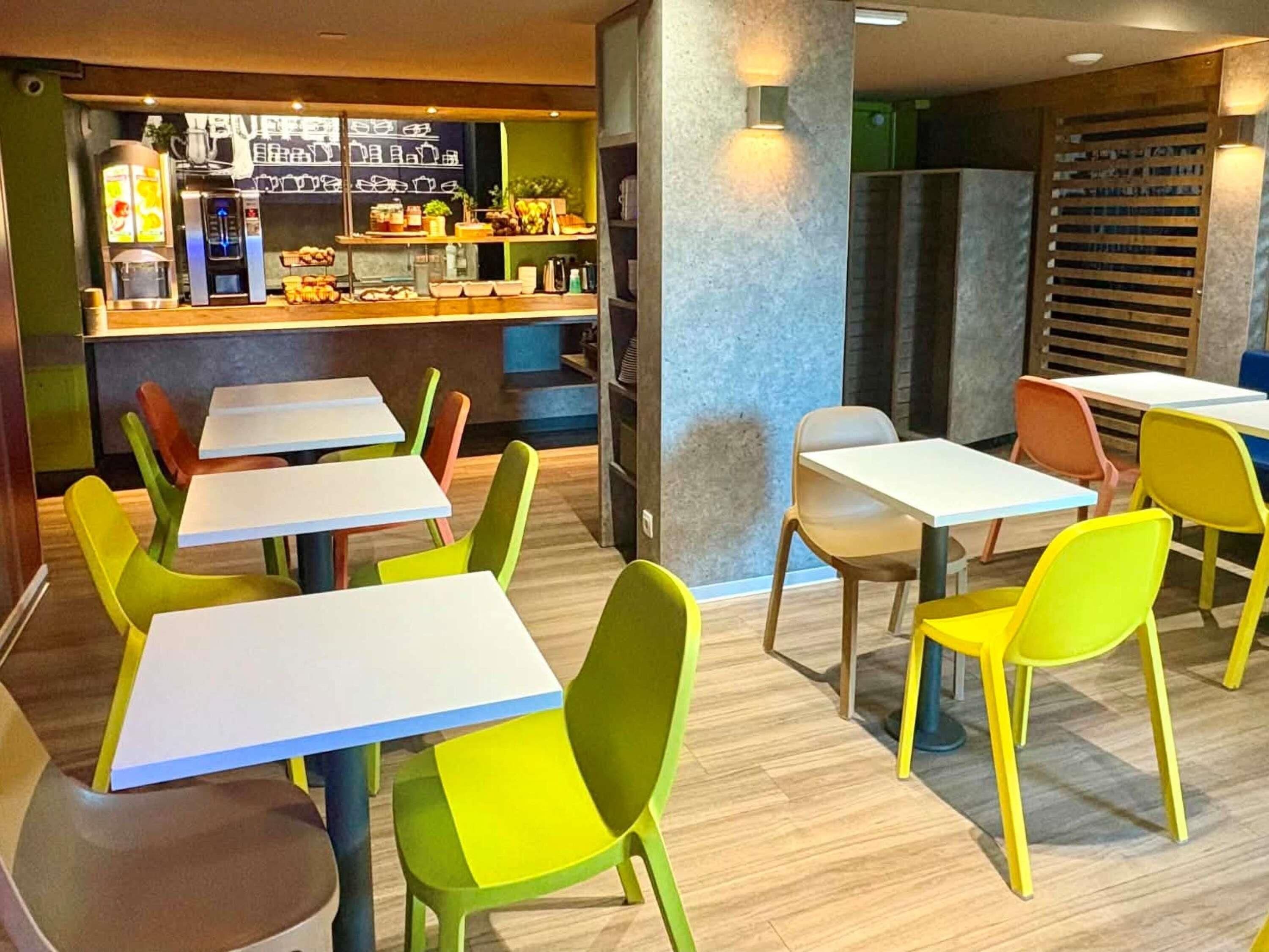 Un restaurante con sillas y mesas coloridas, una barra con productos alimenticios y una decoración interior moderna.