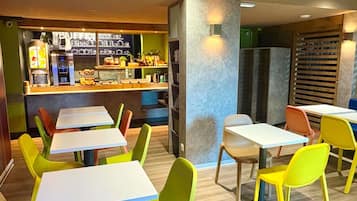 Un restaurante con sillas y mesas coloridas, una barra con productos alimenticios y una decoración interior moderna.