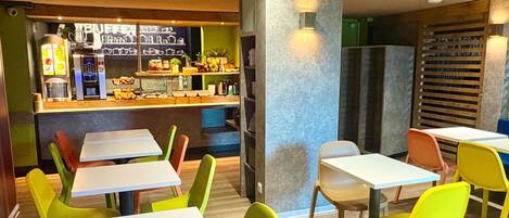 Un restaurante con sillas y mesas coloridas, una barra con productos alimenticios y una decoración interior moderna.