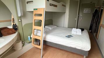 A bunk bed room with a wooden ladder, a small bedside table, a mirror, and a door.