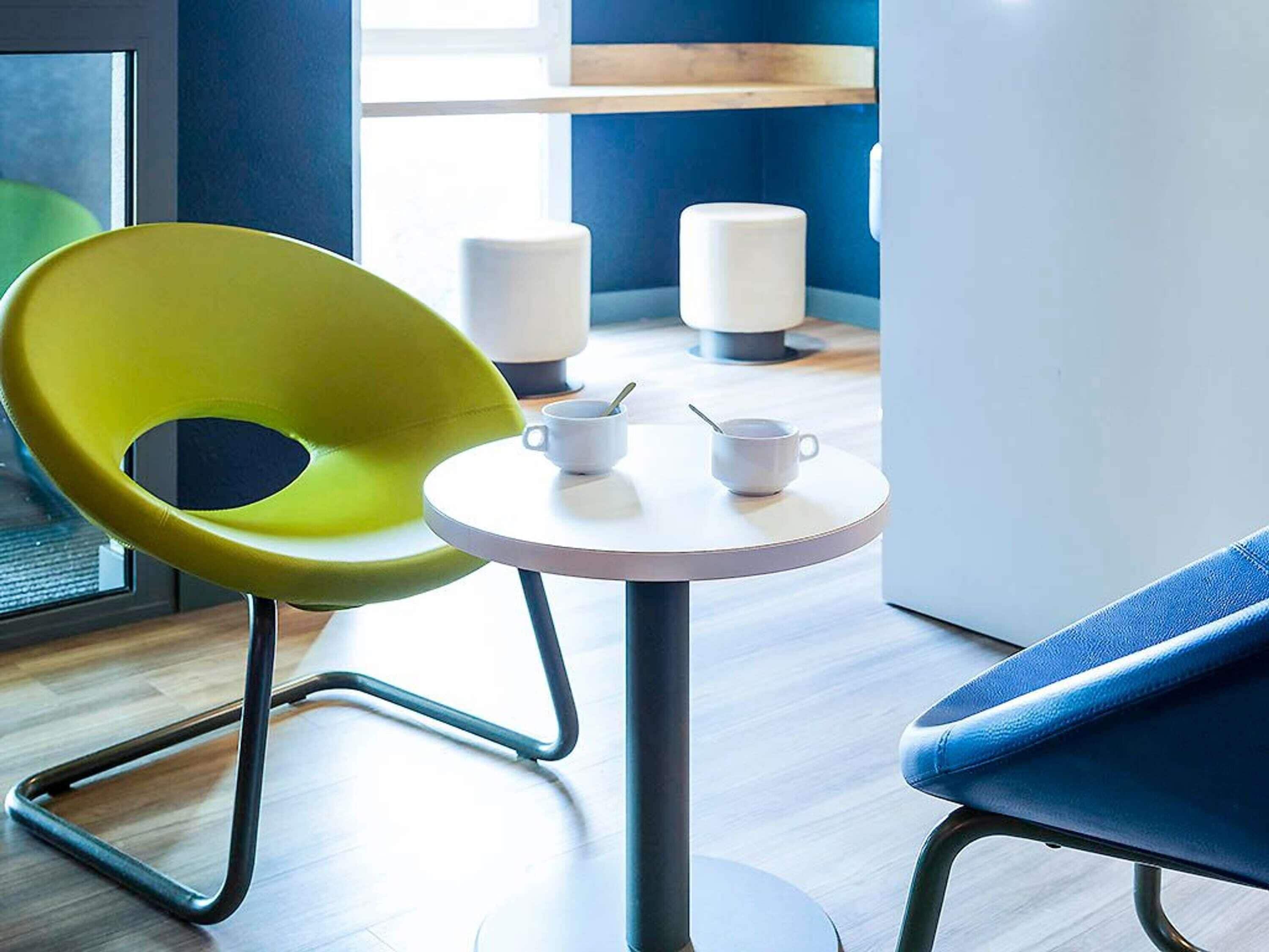 A modern room with a round table, a yellow chair, and a blue sofa.