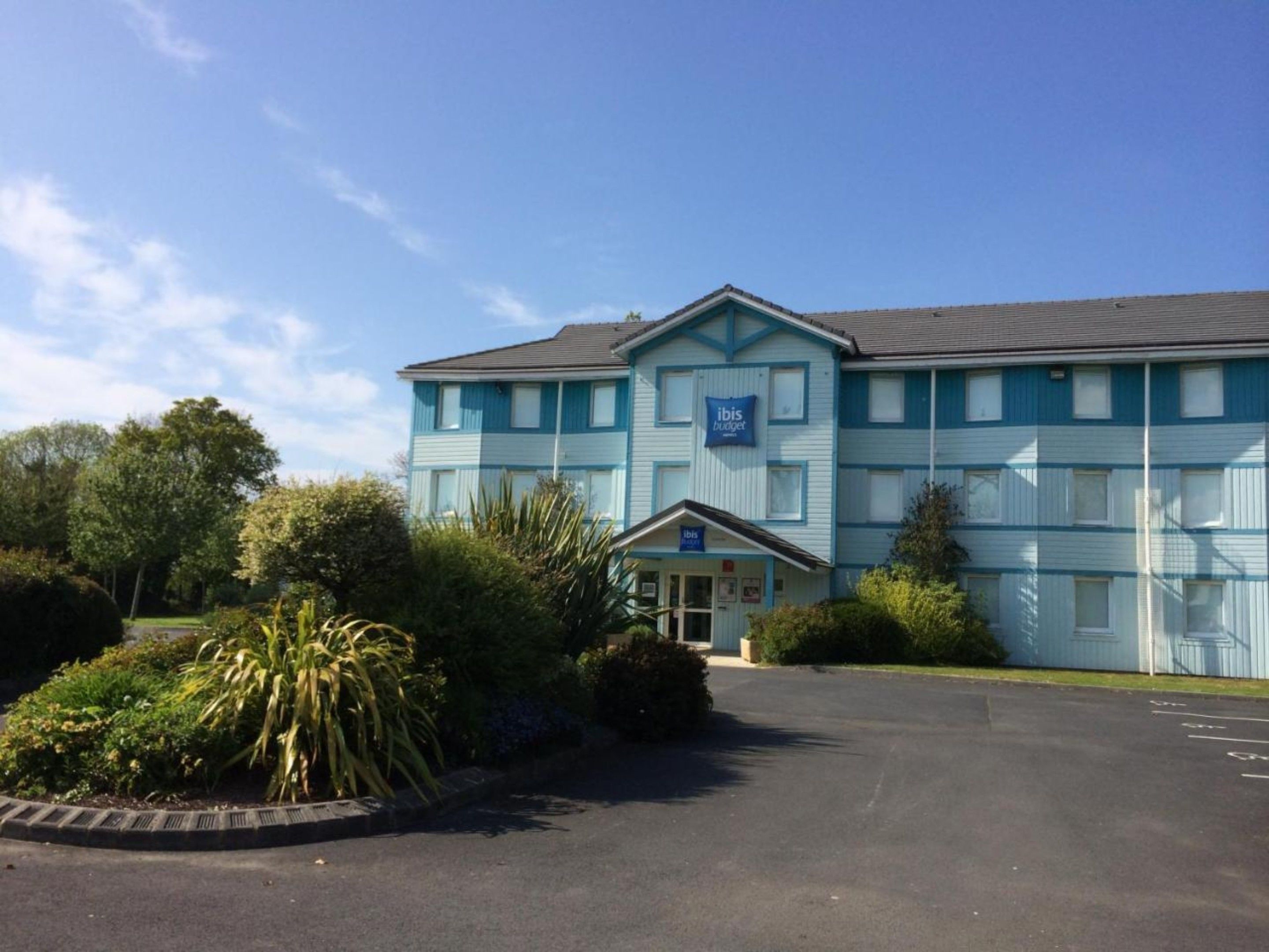 A two-story building with a blue facade and a sign that reads "ibis budget."