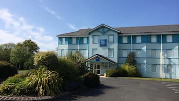 A two-story building with a blue facade and a sign that reads "ibis budget."