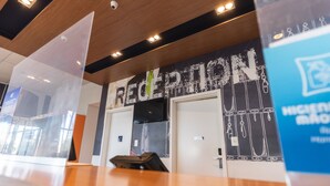 A reception area with a modern design, featuring a reception desk and a wall with a large sign that reads "RECEPTION".