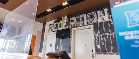 A reception area with a modern design, featuring a reception desk and a wall with a large sign that reads "RECEPTION".