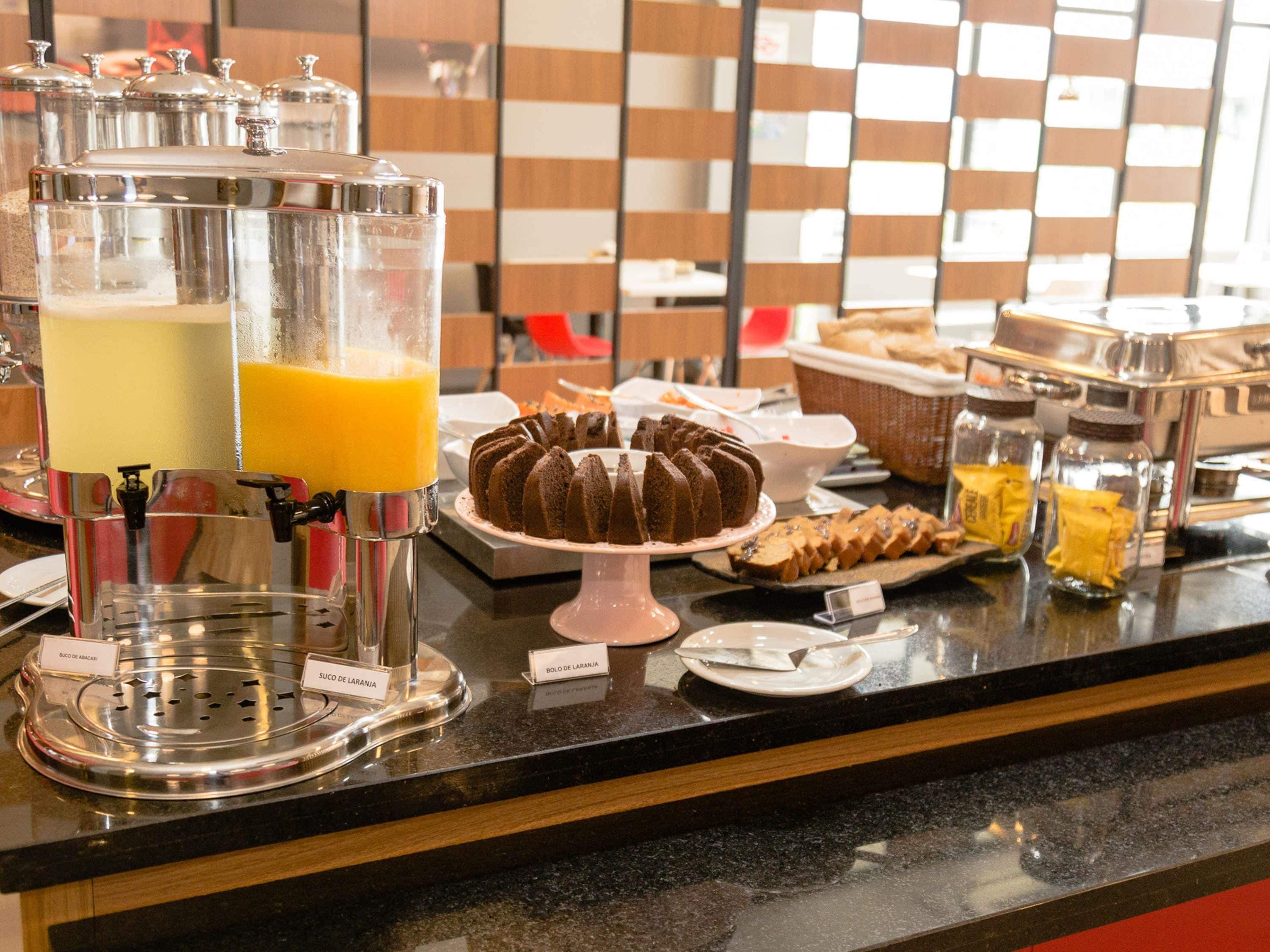 Un bufé de desayuno con diversas opciones de comida y un dispensador de jugo.