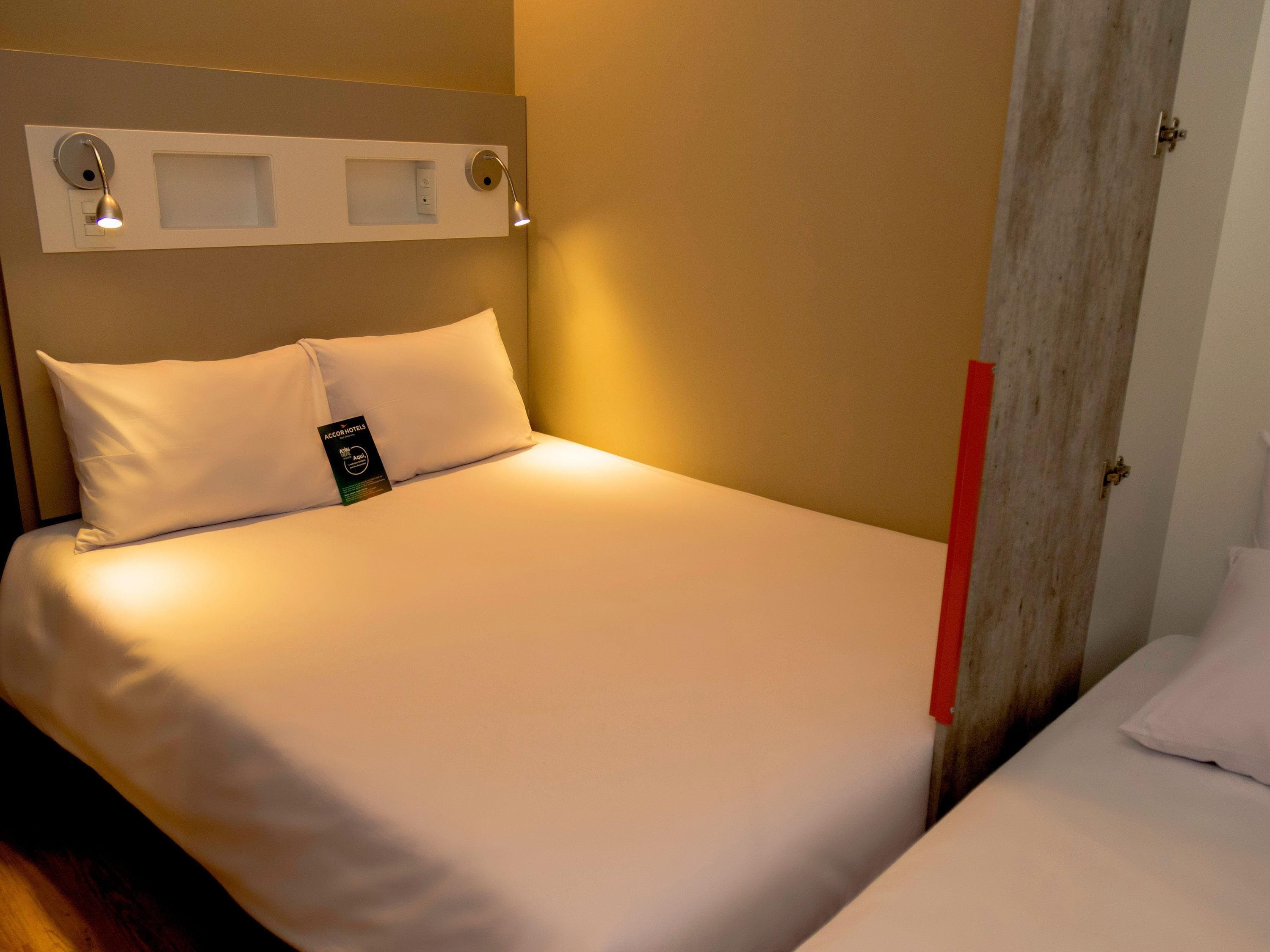 En snyggt bäddad säng med vita sängkläder, en kudde och en etikett som visar vilket hotell det är.
