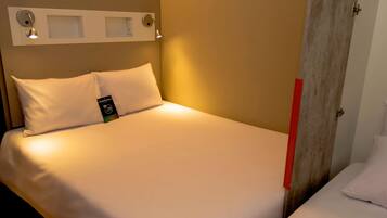 En snyggt bäddad säng med vita sängkläder, en kudde och en etikett som visar vilket hotell det är.