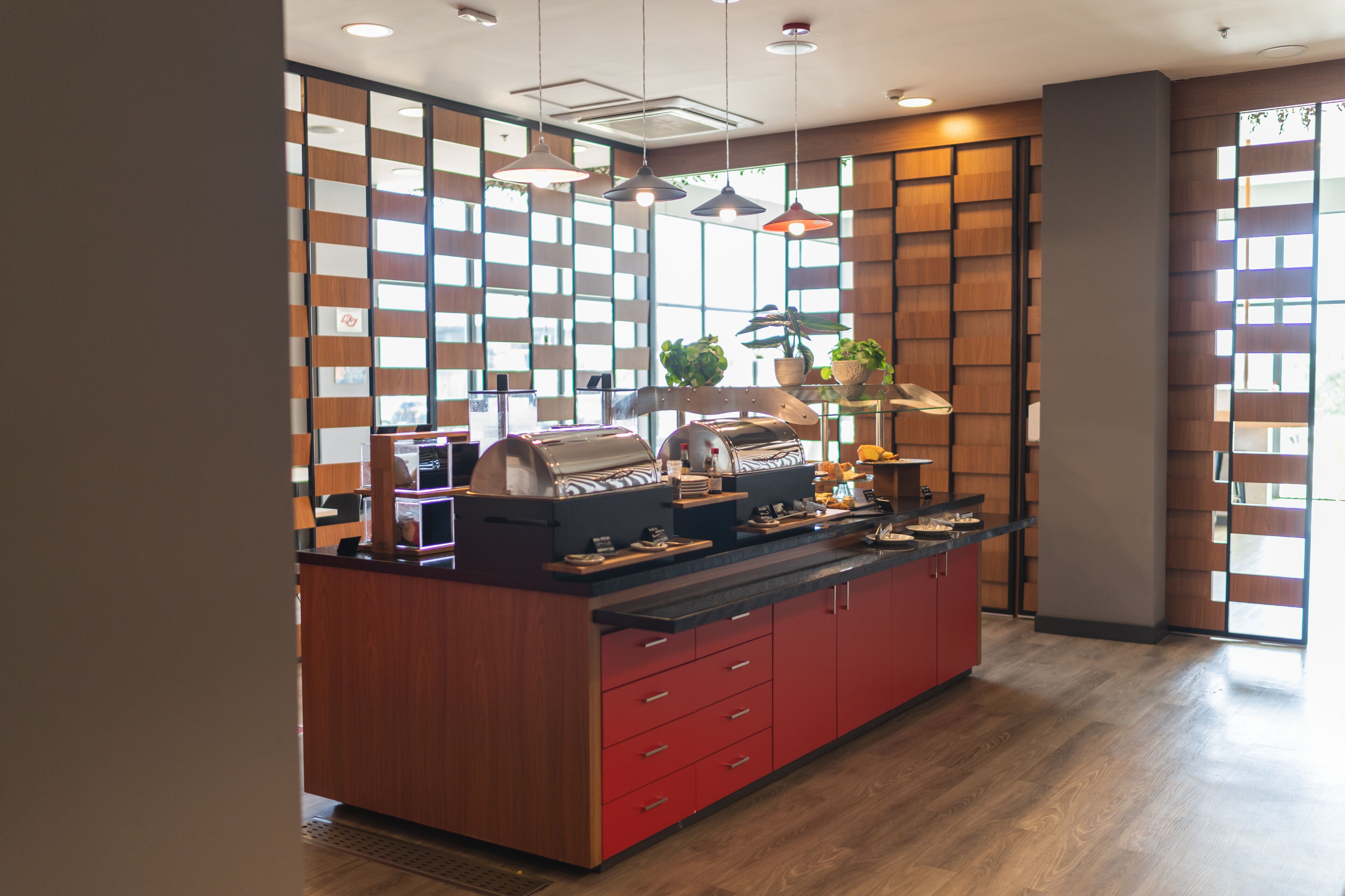 A modern kitchen with a central island, wooden panel walls, and pendant lighting.