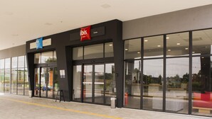 Entrada de hotel con fachada negra, puertas de cristal y un cartel que dice "ibis Lorena".